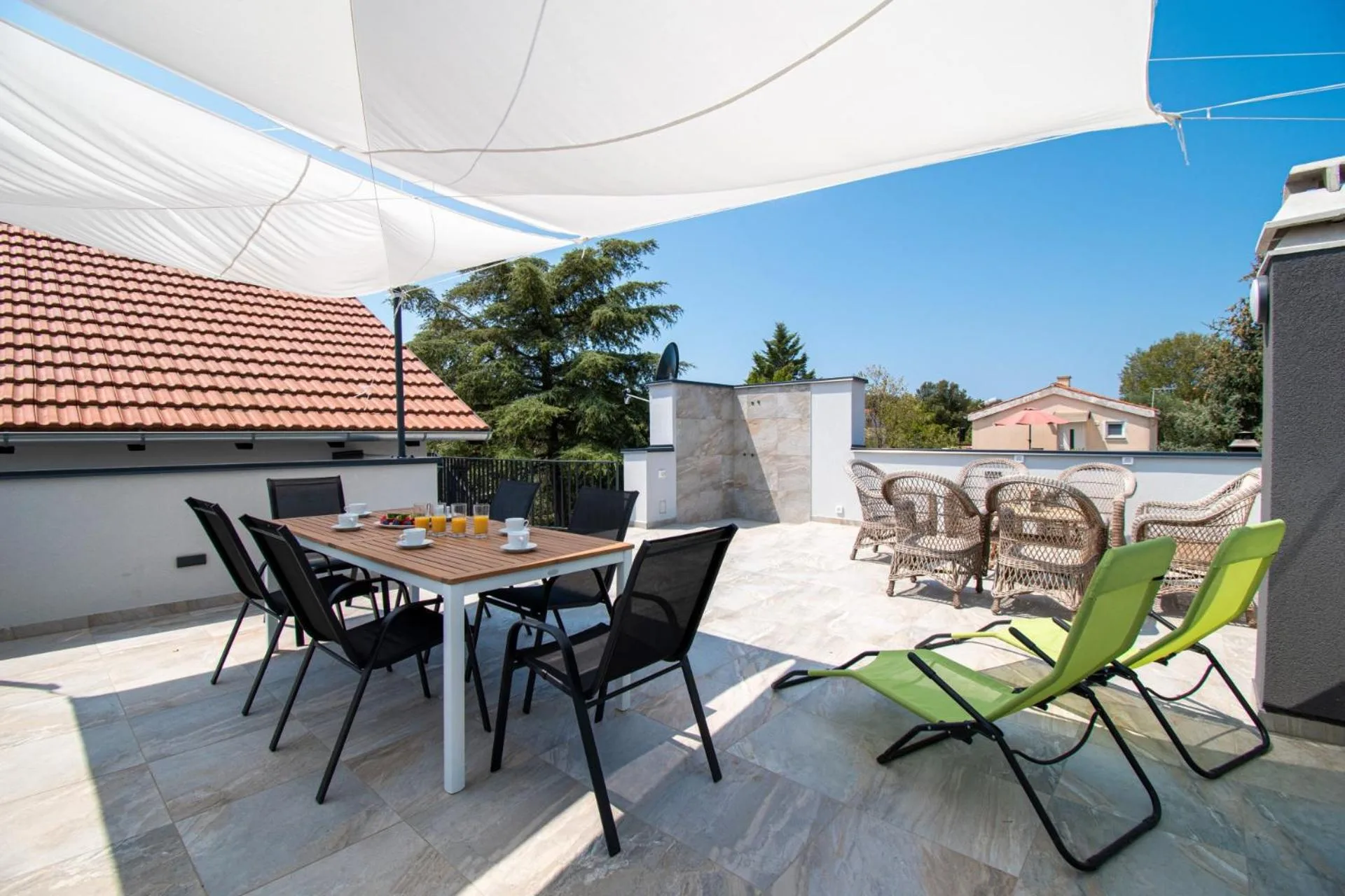Upper terrace with dining table and loungers under the sail shade